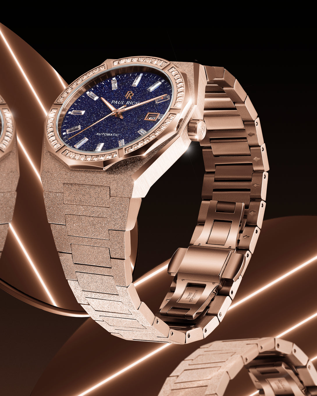 Side view of a rose gold Paul Rich watch with frosted bracelet and blue aventurine dial, reflecting warm light across a mirrored surface. product_visual Quartz | Automatic Side view of a rose gold Paul Rich watch with frosted bracelet and blue aventurine dial, reflecting warm light across a mirrored surface. product_visual Quartz | Automatic