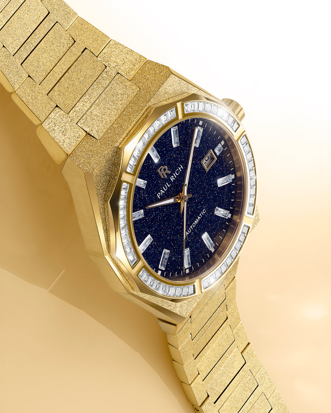 Gold frosted watch with blue aventurine dial and moissanite bezel displayed on a warm beige reflective surface under soft studio light. Quartz | Automatic product_visual Gold frosted watch with blue aventurine dial and moissanite bezel displayed on a warm beige reflective surface under soft studio light. Quartz | Automatic product_visual