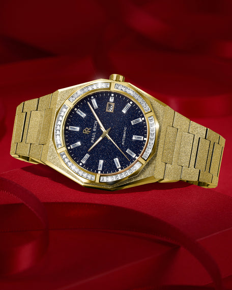 Gold frosted watch with blue aventurine dial and moissanite bezel resting on deep red fabric, highlighting its sparkle and polished finish. Quartz | Automatic product_visual [lifestyle]