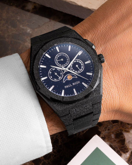 Frosted black moonphase watch on wrist with aventurine dial, calendar subdials, and diamond-dust black bracelet finish. product_visual, [lifestyle]