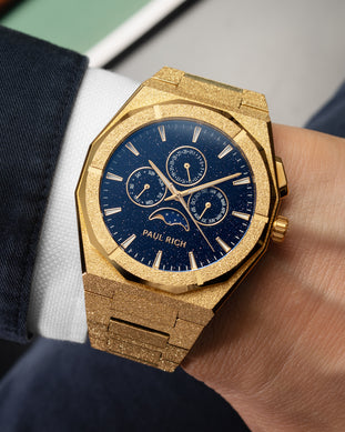 Frosted gold moonphase watch on wrist with aventurine dial, calendar subdials, and shimmering textured gold bracelet. product_visual, [lifestyle]