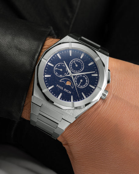Brushed silver moonphase watch on wrist with deep blue aventurine dial, calendar subdials, and steel bracelet. product_visual, [lifestyle]
