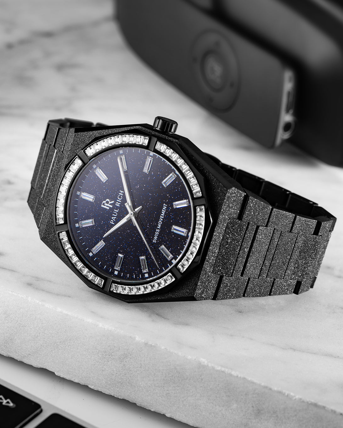 Black frosted watch with aventurine dial and baguette-cut moissanite bezel, displayed on a white marble surface. product_visual, Quartz I Automatic