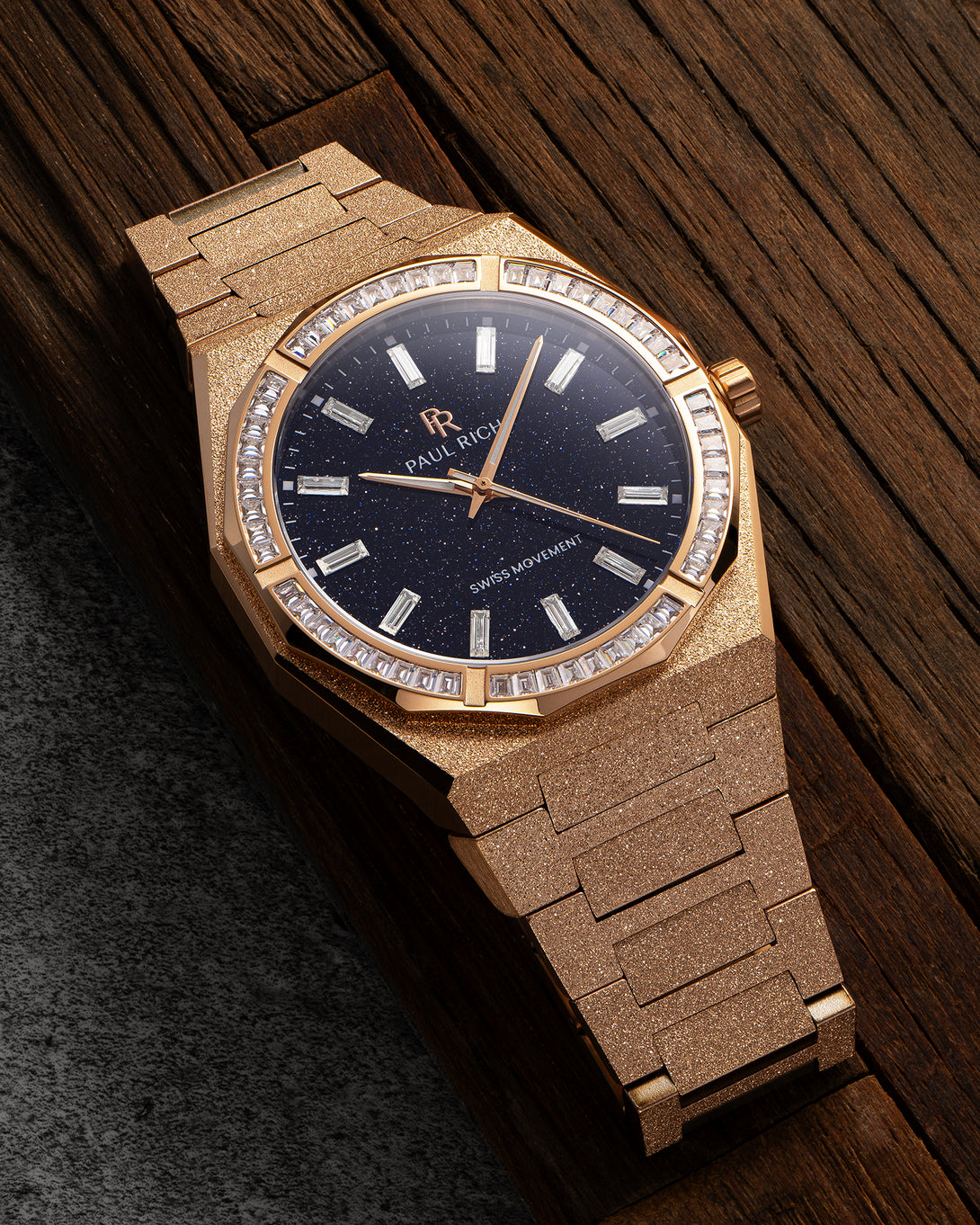 Rose gold frosted watch with aventurine dial and baguette-cut moissanite bezel, displayed on a dark wooden surface. product_visual Quartz I Automatic
