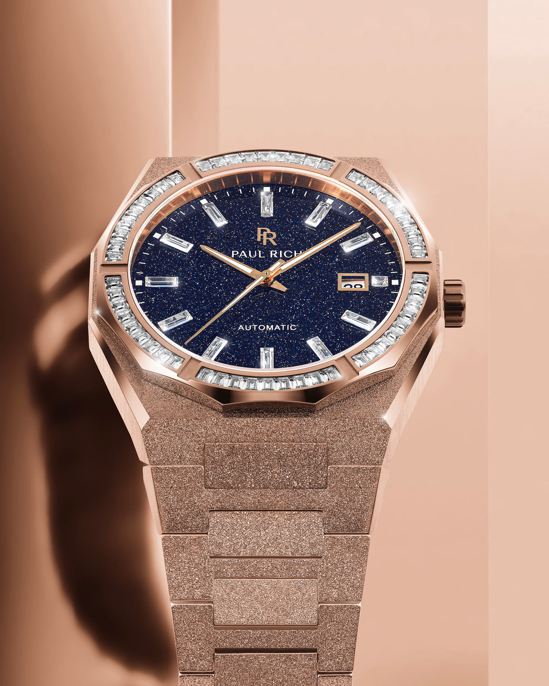 Rose gold Paul Rich watch with frosted bracelet, blue aventurine dial, and gem-set bezel, displayed under warm studio lighting. product_visual Quartz | Automatic