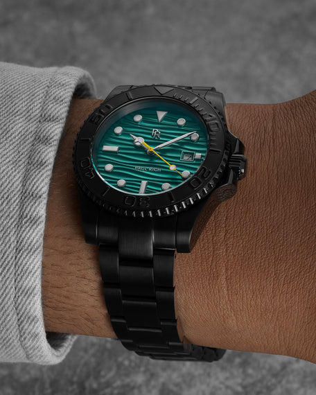Black stainless steel watch with a teal wave-textured dial shown on a wrist, highlighting the bracelet, bezel, luminous markers, and yellow seconds hand. [lifestyle] product_visual