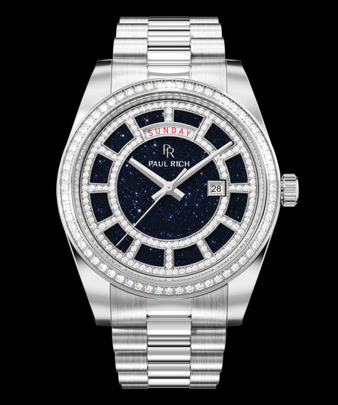 Silver watch with a blue aventurine dial, day and date windows, and a bezel and hour markers set with clear stones on a full stainless-steel bracelet.