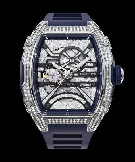 Close-up front view of open dial watch with diamond-set silver case and navy blue strap, shown on transparent background.