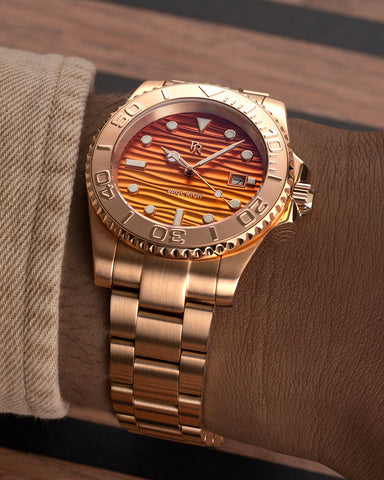 Rose-gold stainless steel watch with an orange wave-textured dial shown on a wrist, highlighting the bracelet, bezel, and dial details. [lifestyle] product_visual